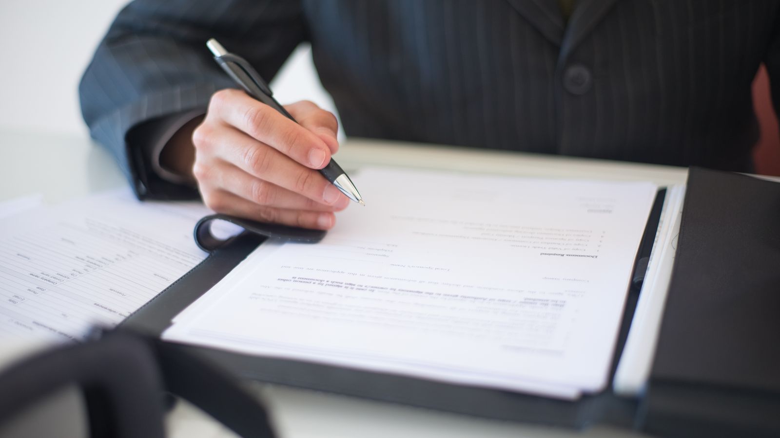 Une main signant un document au stylo, en gros plan