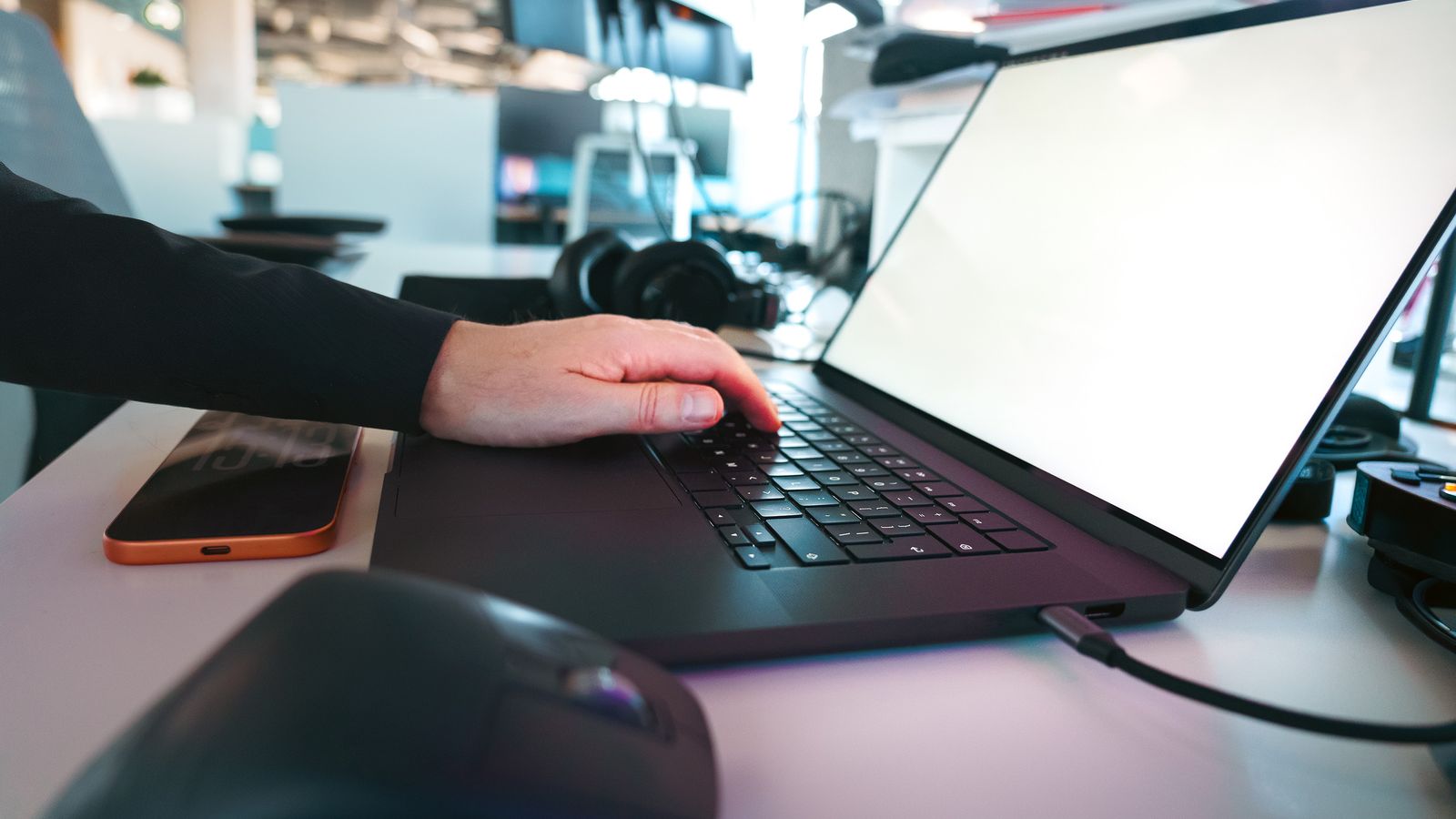 Saisie manuelle sur un clavier d'ordinateur portable dans un environnement de bureau élégant, illustrant la technologie moderne.