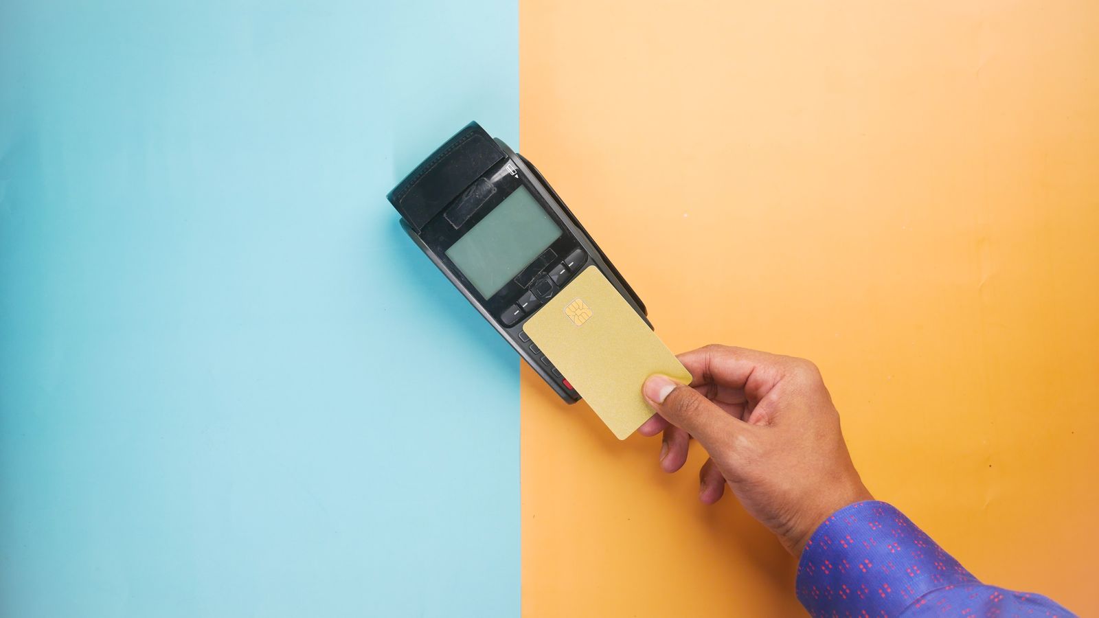 Une main tapant une carte de crédit sur un terminal de paiement pour une transaction sans contact.