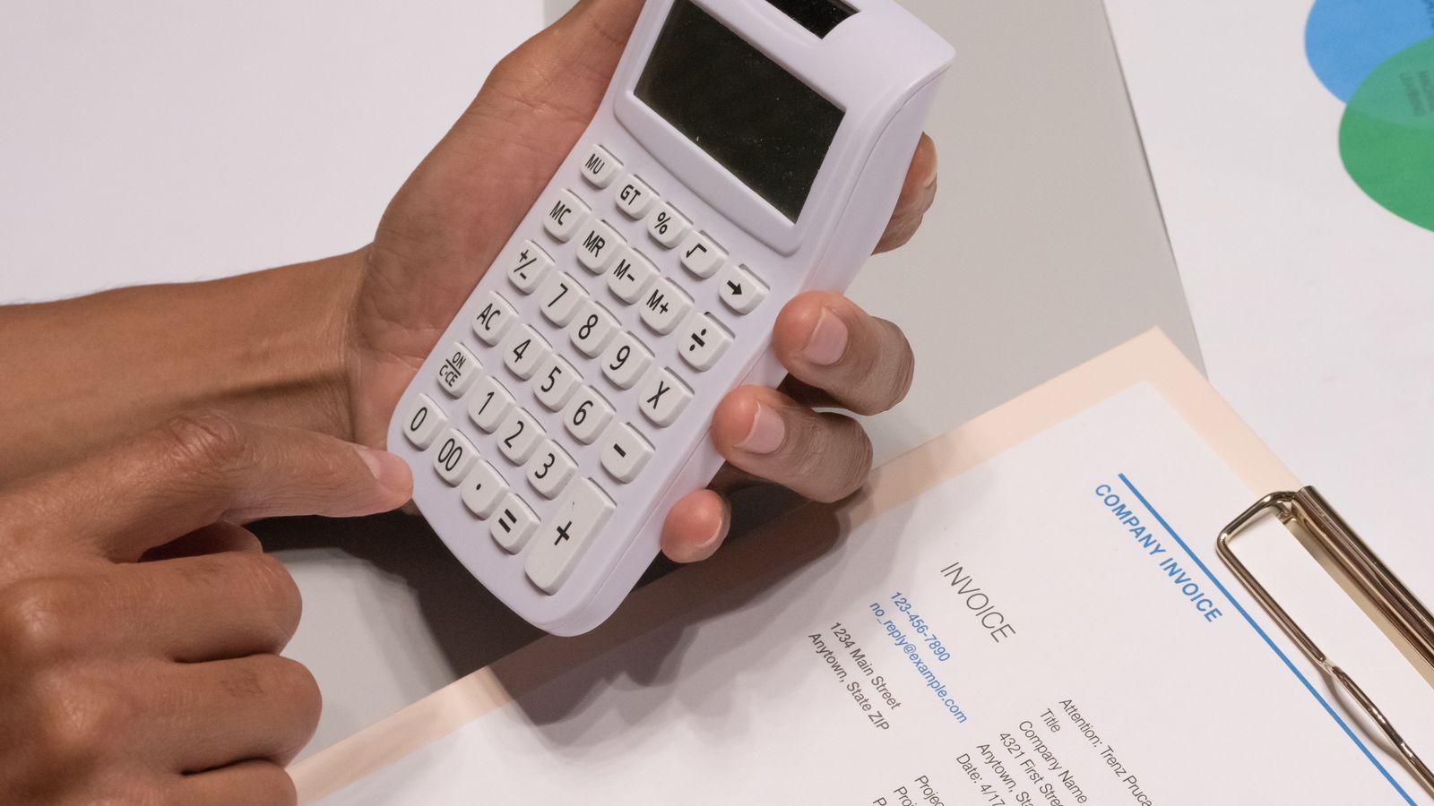 Des mains utilisant une calculatrice posée à côté d'une facture