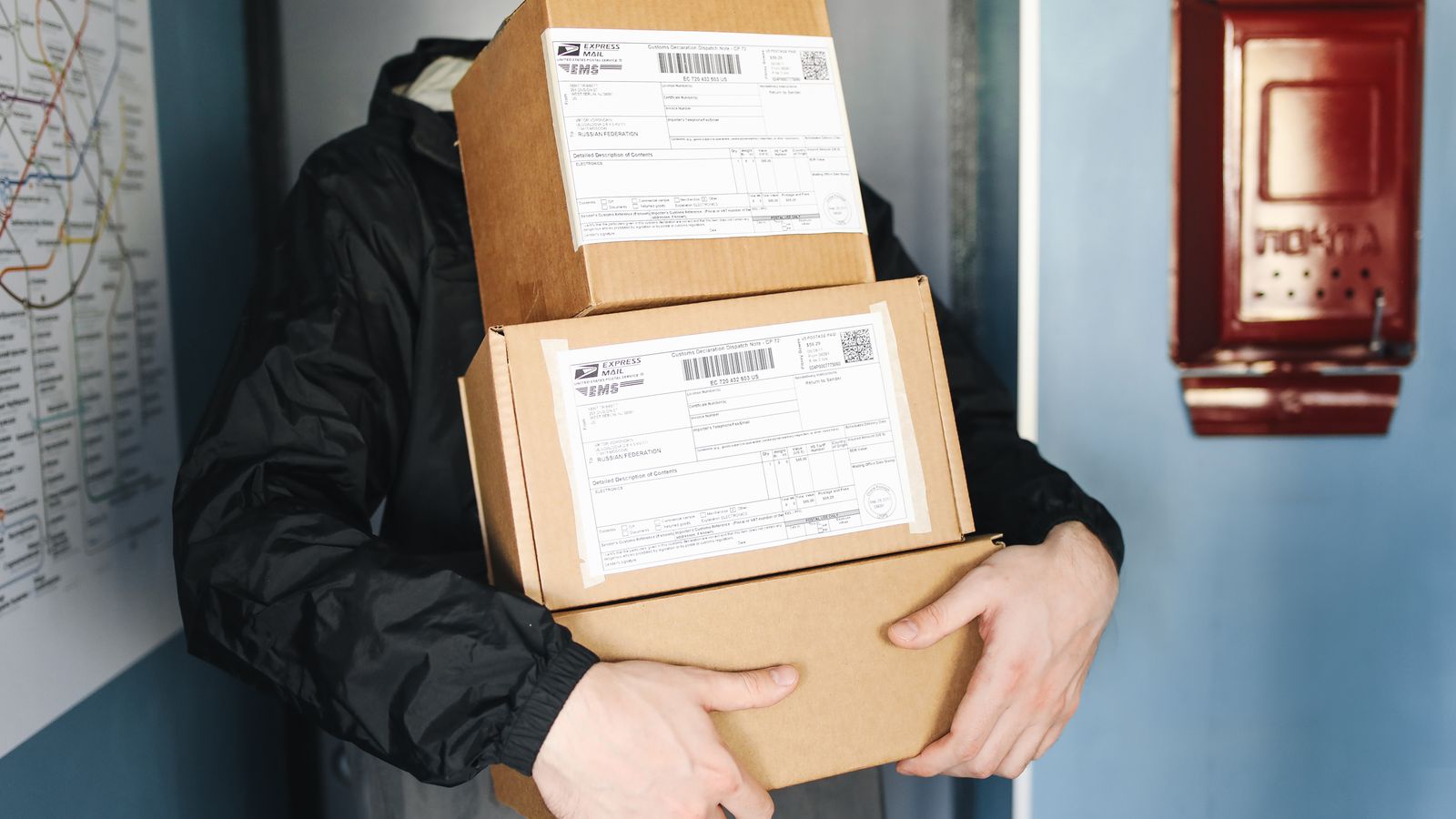 Un livreur portant une pile de colis en carton